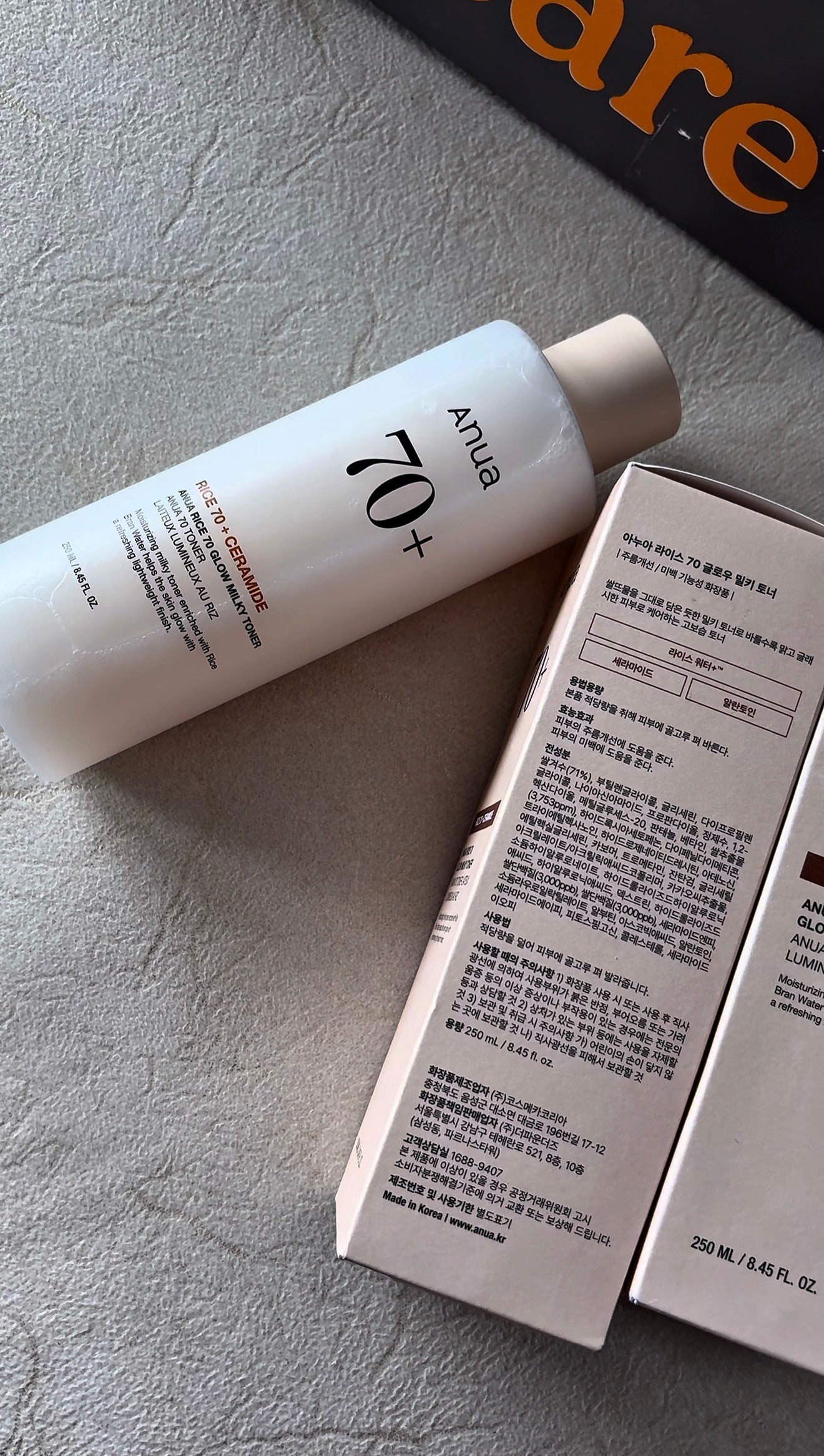 White bottle with text and a box on a gray surface