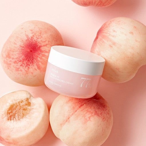 Pink skincare jar with white lid surrounded by peaches on a pink background