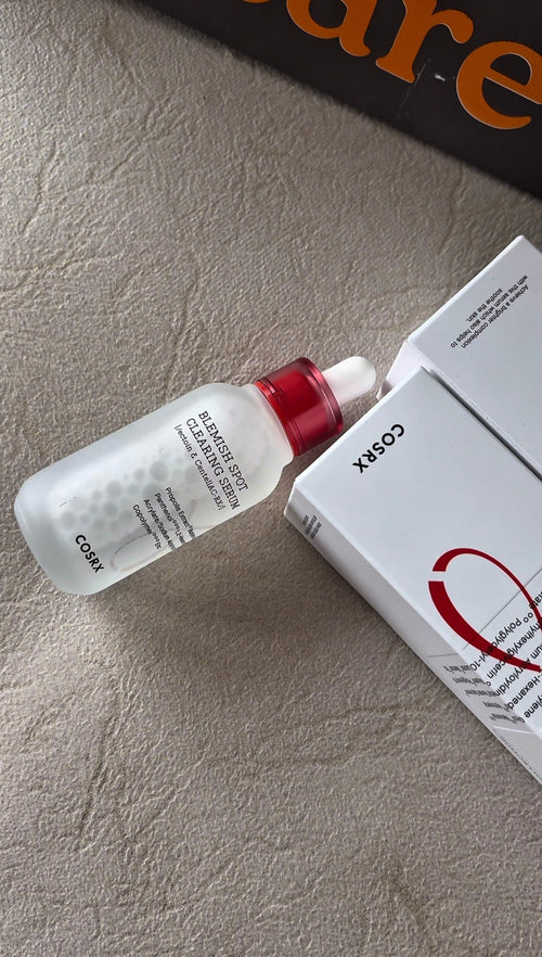 Cosmetic bottle with red cap and white label on a textured surface